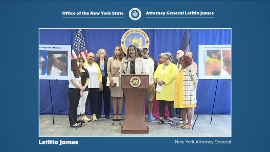 AG James at podium with several people behind her for press conference