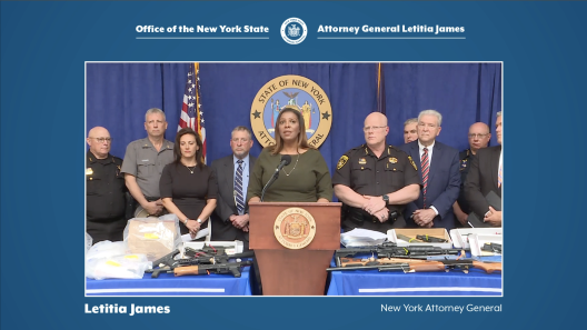 AG James at podium with several people behind her for press conference