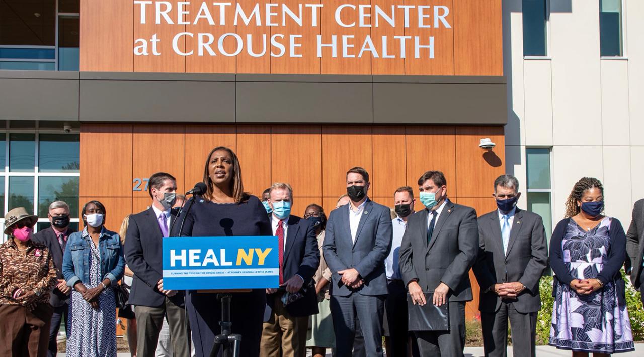 Letitia James stands at a podium with a banner that reads HEAL NY on it, addressing a crowd in front of the Crouse Health center in Syracuse NY