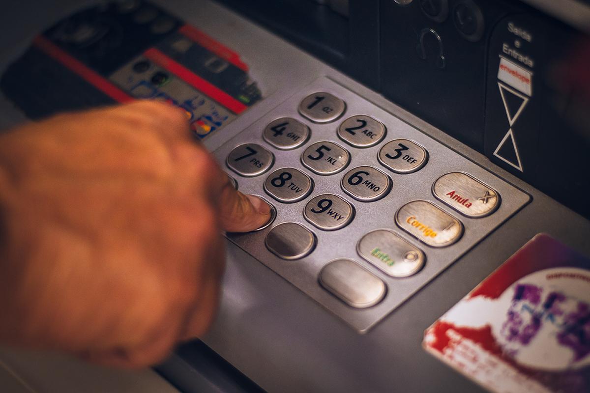 Hand typing on numeric keyboard of atm