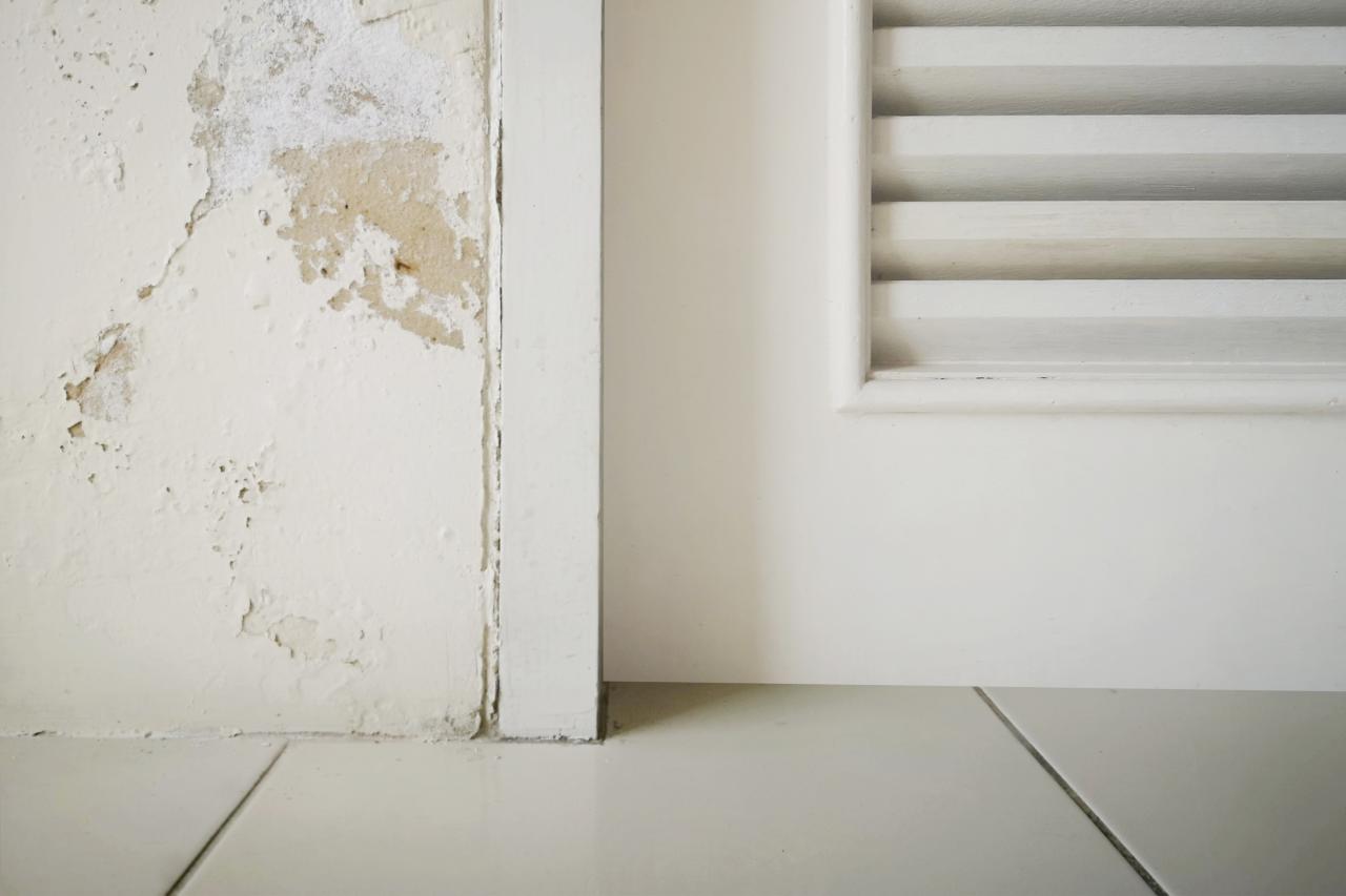 An image of peeling cream-colored paint on a wall next to a door