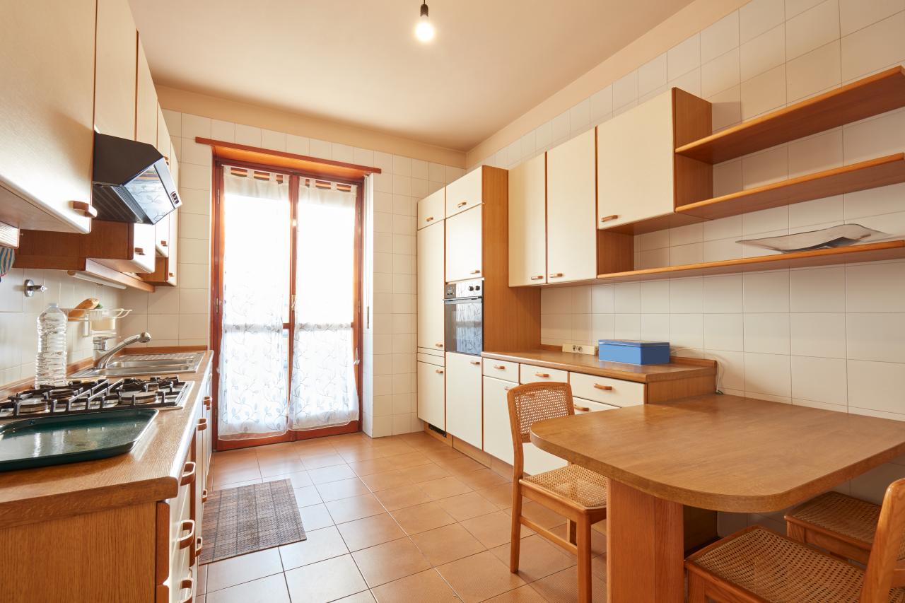 Interior view of an apartment kitchen with a wooden table in view and large windows