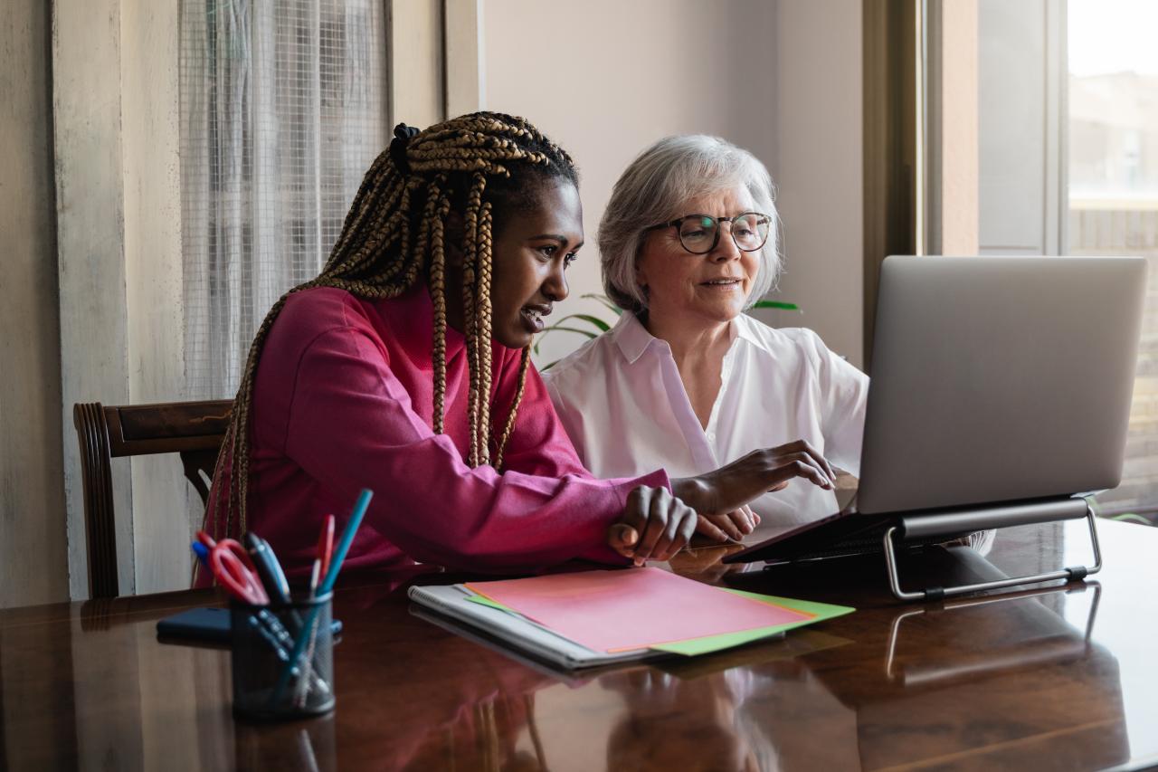 A young person helping an older person use their laptop