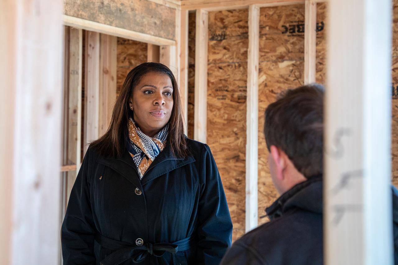 Attorney General James talking to person in house under construction