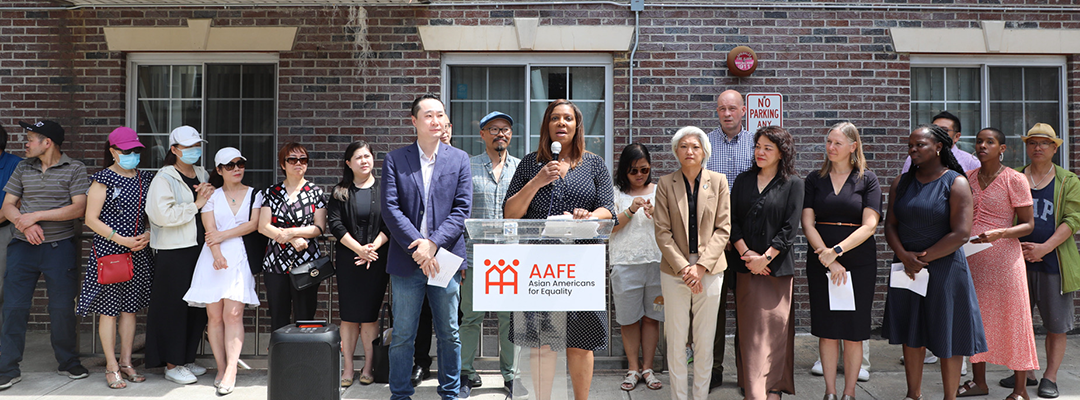 AG James at a podium with a group of people behind her
