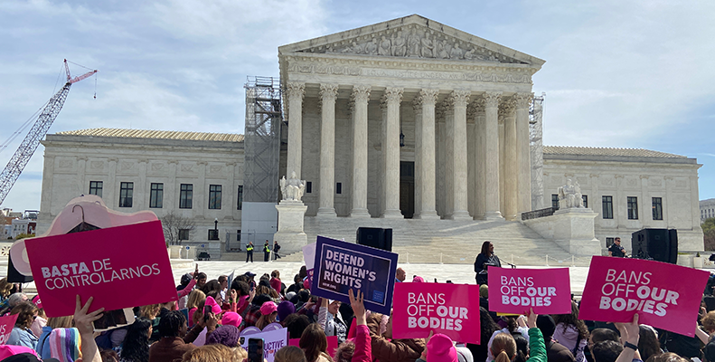 A crowd of people with signs reading "bans off our bodies" in front of the Supreme Court