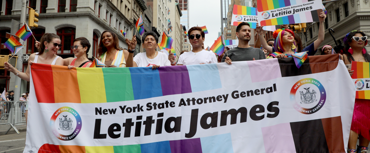 AG James and a group of people marching in pride parade with OAG banner in pride colors