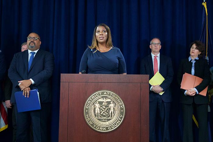 AG James at podium with 3 people behind her