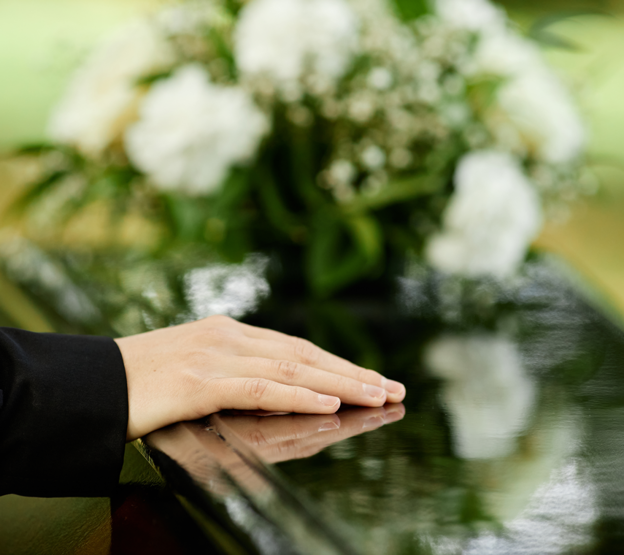 a close up of a hand sitting on a coffin with flowers