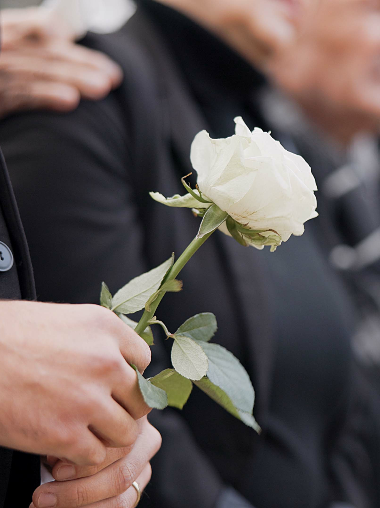 Person holding a rose a a funeral service