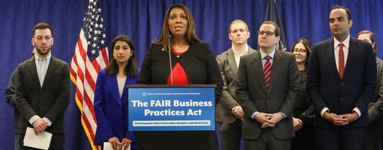 AG James standing with a group of people at a podium with a sign that reads The FAIR Business Practices Act 