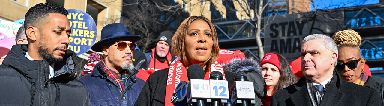 AG James at a podium with a group of people behind her