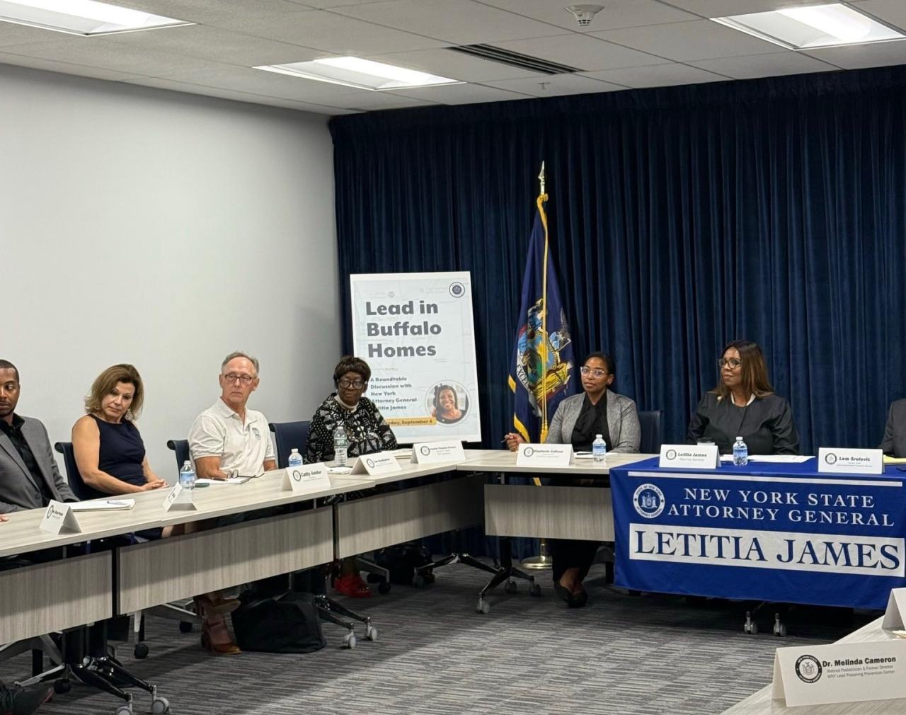 AG James at a table with a group of people and a poster that reads Lead in Buffalo Homes
