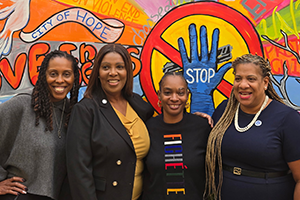 AG James with three other people in front of a city of hope mural