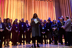 AG James on stage with a large group of people behind her