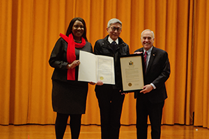 AG James holding a presentation folder with two other people