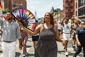AG James waving a fan walking in pride parade with many others around her