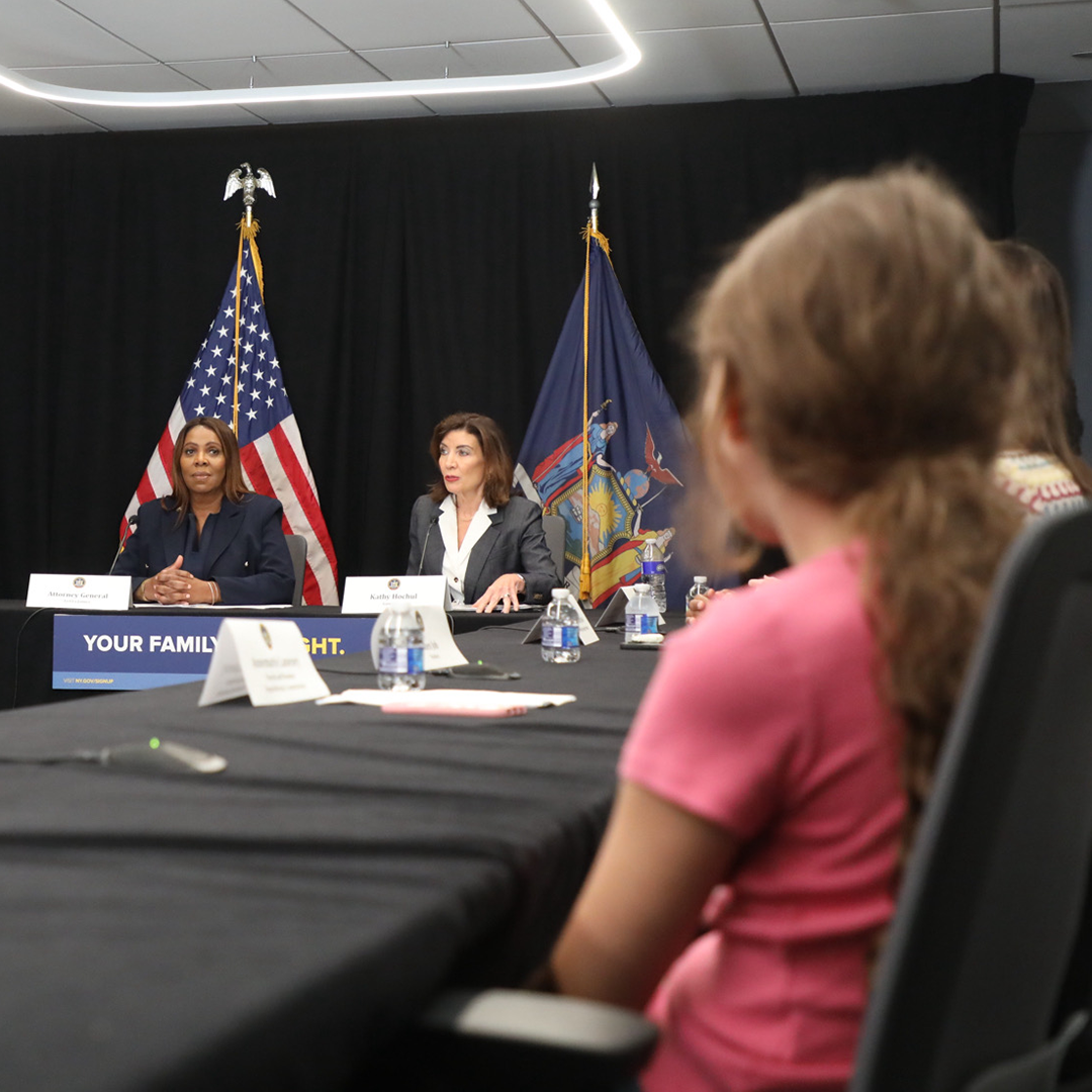 AG James at a table with Gov Hochul, parents and kids